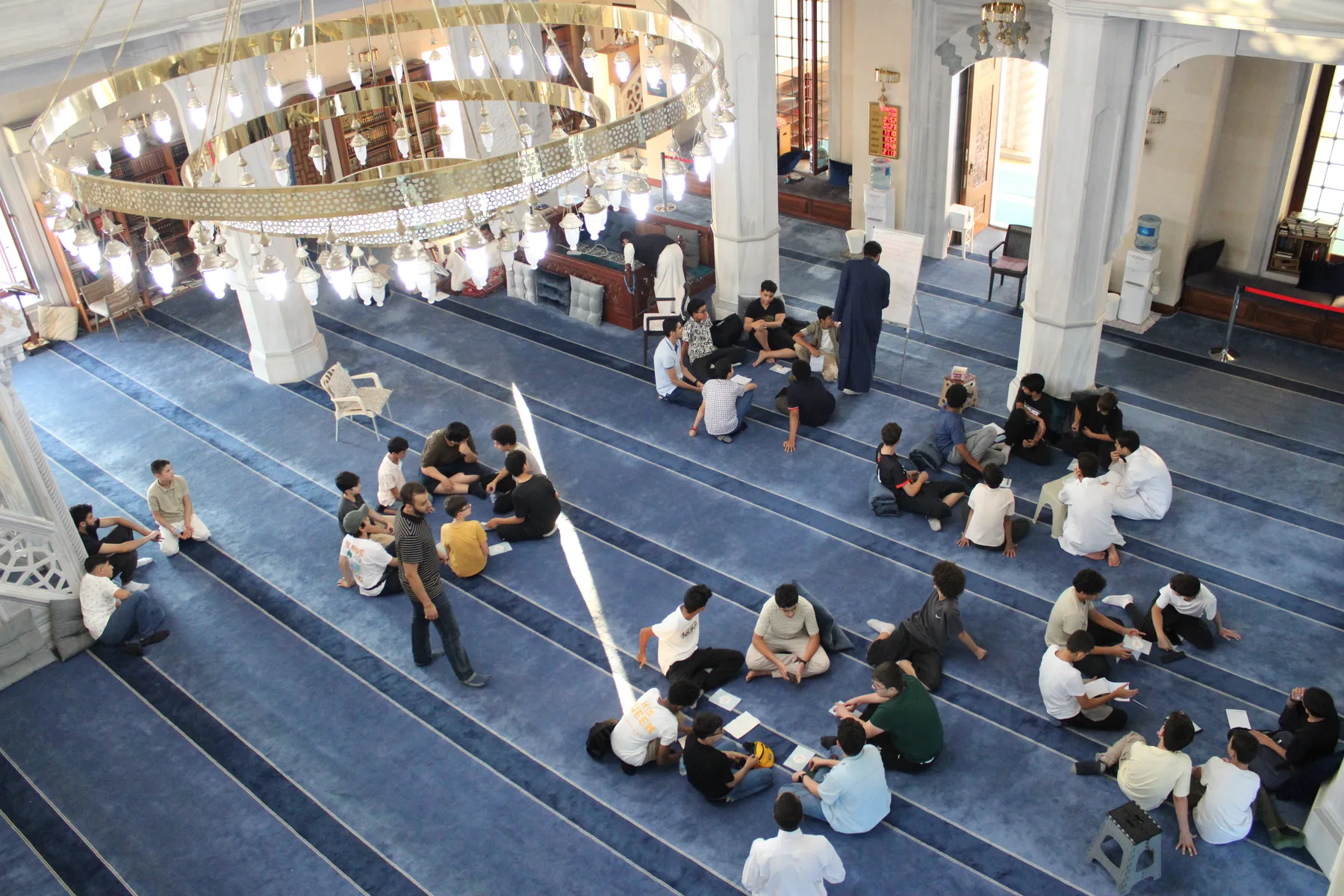 The hall splits into small circles, a teacher to each group.